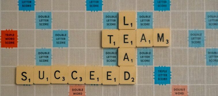Scrabble tiles spelling out "team succeed lead"